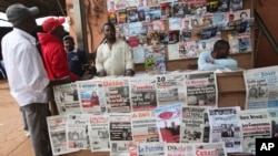 FILE - People read local newspapers with election headlines in Yaounde, Cameroon.