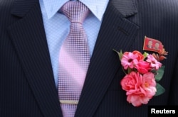 FILE - A bridegroom wears a badge with portraits of late North Korean leaders Kim Il Sung and Kim Jong Il in Pyongyang, North Korea, Sept. 11, 2018.