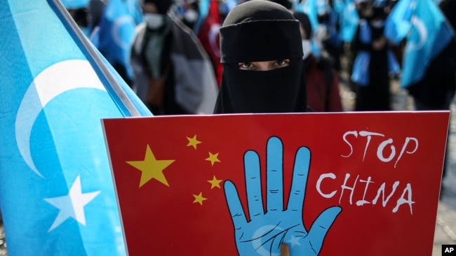 A protester from the Uyghur community living in Turkey holds up an anti-China placard during a protest against the visit of China's Foreign Minister Wang Yi to Turkey, in Istanbul, Thursday, March 25, 2021. (AP Photo/Emrah Gurel)