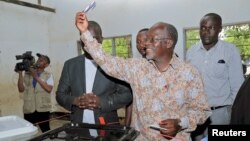 Tanzanian presidential candidate of the ruling CCM party, John Magufuli, displays his ballot paper before casting his vote in the presidential and parliamentary election at his hometown Chato district, in Geita region, Tanzania, Oct. 25, 2015.