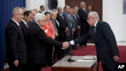 Palestinian Foreign Minister Riyad al-Malik, right, shakes hands with President Mahmoud Abbas during a swearing-in ceremony of its unity government in the West Bank city of Ramallah, June 2, 2014.