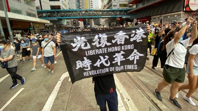 7月1日港版国安法实施第一日,数以万计香港人聚集在铜锣湾上街游行,有人高举被当局批评有港独含意的反送中运动旗帜(美国之音/汤惠芸)