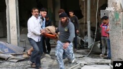 This photo provided by the anti-government activist group Aleppo Media Center (AMC), an anti-Bashar Assad activist group, which has been authenticated based on its contents and other AP reporting, shows Syrian men carrying a covered dead body after a government airstrike attack in the al-Mayssar neighborhood, in Aleppo, April 3, 2014. 