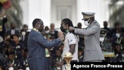 Le président sénégalais Macky Sall décore l'entraîneur-chef du Sénégal Aliou Cissé lors de la cérémonie de décoration des Lions de la Téranga près du Palais de la République à Dakar, le 8 février 2022. (AFP/SEYLLOU)