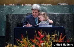 ລັດຖະມົນຕີການຕ່າງປະເທດສະຫະລັດ ທ່ານ John Kerry ເຊັນຂໍ້ຕົກລົງ ວ່າດ້ວຍການປ່ຽນແປງດິນຟ້າອາກາດ ປາຣີ ທີ່ສຳນັກງານໃຫຍ່ ສປຊ ໂດຍມີຫຼານສາວຂອງທ່ານ ນັ່ງຕັກຢູ່
