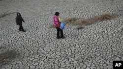 People walk on a dried up pond at Hanzhuang village in Tangyin county in central China's Henan province (File Photo)