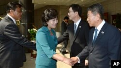 The head of North Korea's delegation Kim Song Hye, center, shakes hands with South Korean delegate Kwon Young-yang, right, upon their arrival for a meeting at the southern side of Panmunjom, in Paju, north of Seoul, South Korea, June 9, 2013. (Photo released by S. Korean Unification Ministry)