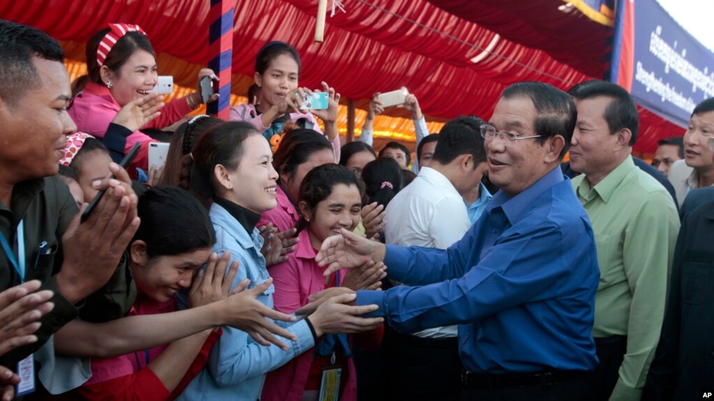 Prime Minister Hun Sen greets garment workers during a visit to a factory outside of Phnom Penh, Cambodia, Wednesday, Aug. 30, 2017. Hun Sen embarked on a country-wide trip to visit the nation's factory workers to hear their hopes and concerns in person. (AP Photo/Heng Sinith)