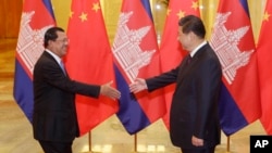 Cambodian Prime Minister Hun Sen (L) shakes hands with China's President Xi Jinping before a meeting at the Great Hall of the People in Beijing, Nov. 7, 2014.