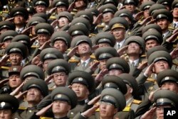 In this, April 15, 2017, photo, North Korean soldiers salute as their national anthem is played during a military parade to celebrate the 105th birth anniversary of Kim Il Sung, in Pyongyang.