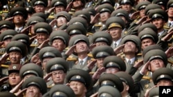 In this, April 15, 2017, photo, North Korean soldiers salute as their national anthem is played during a military parade to celebrate the 105th birth anniversary of Kim Il Sung, in Pyongyang.