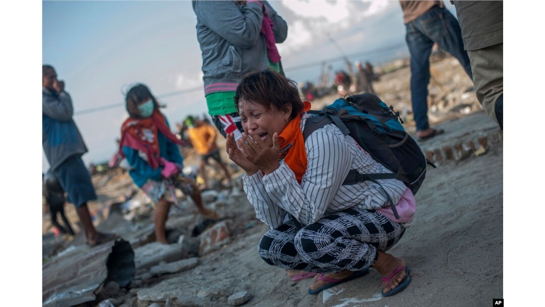 Residents react as rescuers recover the body of a tsunami victim in a village heavily damaged by Friday's tsunami in Palu, Central Sulawesi, Indonesia Indonesia, Oct. 3, 2018.