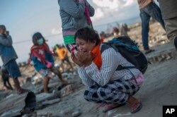 Residents react as rescuers recover the body of a tsunami victim in a village heavily damaged by Friday's tsunami in Palu, Central Sulawesi, Indonesia Indonesia, Oct. 3, 2018.