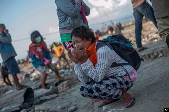 Residents react as rescuers recover the body of a tsunami victim in a village heavily damaged by Friday's tsunami in Palu, Central Sulawesi, Indonesia Indonesia, Oct. 3, 2018.
