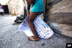 A girl plays with election ballots she found strewn on the street, after a voting center was closed by authorities when fistfights broke out inside during parliamentary elections in Port-au-Prince, Haiti, Aug. 9, 2015.