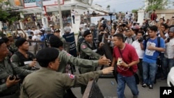 FILE - Riot police officers stop journalists from entering a blocked main street near the Cambodia National Rescue Party (CNRP) headquarters, on the outskirts of Phnom Penh, Cambodia, Monday, May 30, 2016.