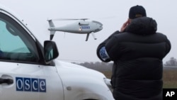 FILE - A member of the Organization for Security and Cooperation in Europe (OSCE) mission to Ukraine watches one of the watchdog's drone take off near the city of Mariupol, eastern Ukraine, Oct. 23, 2014. 