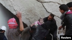 Halepliler hava saldırısının ardından yıkılan bir binanın altından bir çocuğu kurtarıyor