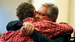 Randy Scroggins, pastor at New Beginnings Church of God, right, embraces Mathew Downing, who was spared during a shooting at Umpqua Community College, during a church service at New Beginnings in Roseburg, Ore., Oct. 4, 2015.