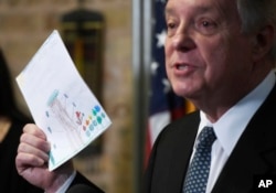 U.S. Sen. Dick Durbin, D-Ill., holds a card written by a Chicago child at a news conference, June 22, 2018, in Chicago.