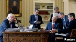 FILE - U.S. President Donald Trump, left to right, joined by Chief of Staff Reince Priebus, Vice President Mike Pence, senior advisor Steve Bannon, Communications Director Sean Spicer and National Security Advisor Michael Flynn, speaks by phone with Russia's President Vladimir Putin in the Oval Office at the White House in Washington, Jan. 28, 2017.