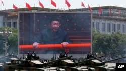 Chinese President Xi Jinping is displayed on a big screen as Type 99A2 Chinese battle tanks roll across during a parade commemorating the 70th anniversary of Japan's surrender during World War II from Tiananmen Gate, in Beijing, Sept. 3, 2015.