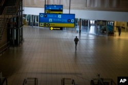 A man walks through a deserted part of Johannesburg's OR Tambo's airport, South Africa, Nov. 29, 2021. The World Health Organization urged countries around the world not to impose flight bans on southern African nations due to concern over the new omicron variant.
