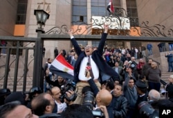 FILE - Khaled Ali, center, celebrates with other lawyers after winning a landmark case against the government, blocking its attempts to hand over control of two strategic Red Sea islands to Saudi Arabia, in Cairo, Egypt, Jan. 16, 2017. On Sept. 25, 2017, an Egyptian court sentenced Ali to three months in prison over a charge of offending public morals for making an obscene gesture.