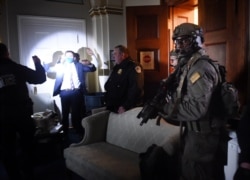 Congress staffers hold up their hands while Capitol Police Swat teams check everyone in the room as they secure the floor of Trump suporters in Washington, DC on January 6, 2021