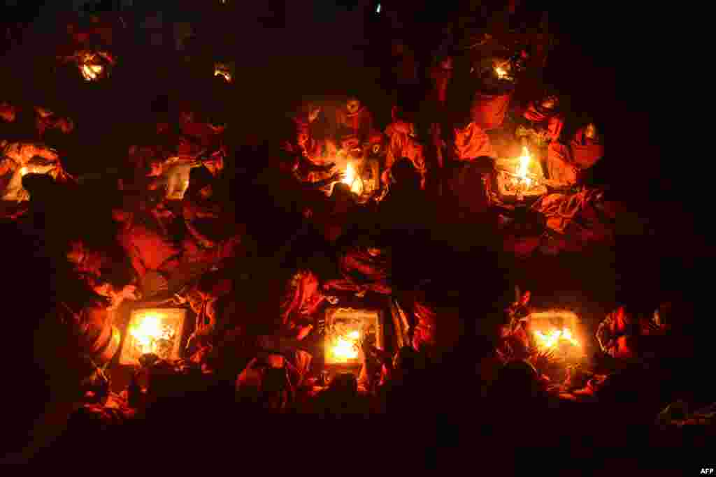 Perempuan Hindu Nepal menghangatkan diri di perapian setelah mandi di Sungai Shali yang suci di pinggiran Kathmandu.