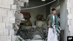 یک مامور یمنی در حال نگهبانی در مقابل حفره ایجاد شده در ساختمان محل سکونت سفیر ایران در صنعا، پس از انفجار بمب – ۱۲ آذر ۱۳۹۳ 