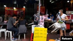 Adulwitch Tangsupmanee, 42, wearing a face mask to prevent the spread of the coronavirus disease (COVID-19), holds up a plastic chair for a customer at his late father's food stall in Bangkok's Chinatown, Thailand, October 6, 2021. (REUTERS/Athit Perawongmetha)