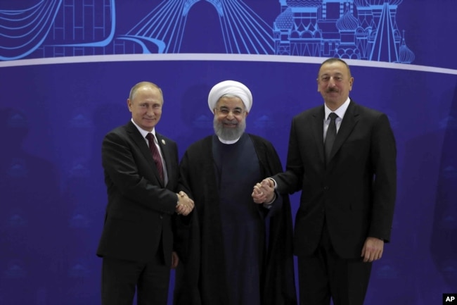 In this photo released by the office of the Iranian Presidency, Iranian President Hassan Rouhani, center, Russian President Vladimir Putin, left, and Azerbaijan's President Ilham Aliyev, right, shake hands after their trilateral meeting in Tehran, Iran, Nov. 1, 2017.