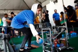 Kawsar Rashan, 15, dari Afghanistan, mengambil bola yang dikumpulkan dari robot tim putri Afghanistan selama latihan setelah pertama kali berkompetisi di First Global Robotics Challenge, Senin, 17 Juli 2017, di Washington. (Foto: AP/Jacquelyn Martin)