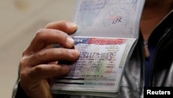 FILE - A member of the Al Murisi family, Yemeni nationals who were denied entry into the U.S. last week because of the recent travel ban, shows the cancelled visa in their passport from their failed entry to reporters.