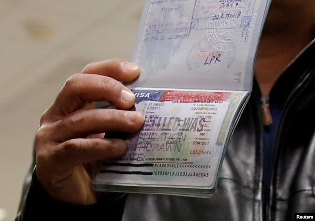 FILE - A Yemeni national who was denied entry into the U.S. earlier this because of the Trump administration's travel ban, shows the cancelled visa in his passport from his failed entry to reporters as he successfully arrives to be reunited with his family, at Washington Dulles International Airport in Chantilly, Virginia, Feb. 6, 2017.