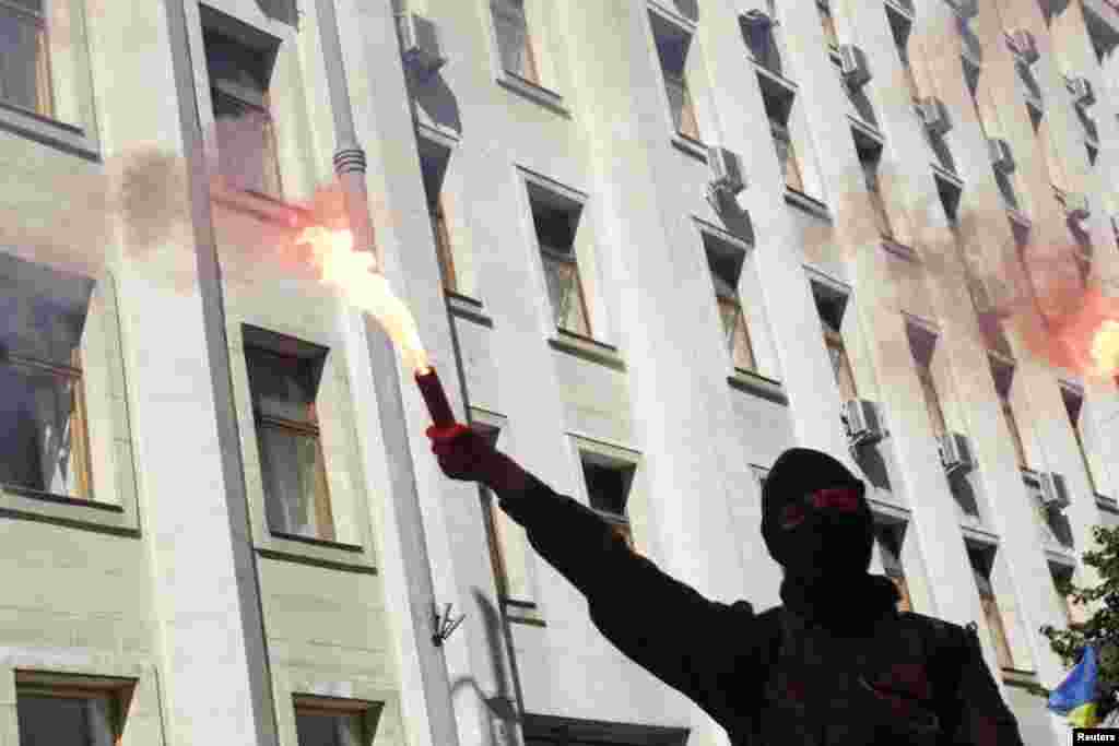 A protester lights a flare during a rally against the law to provide separatist-held regions with a special status near the Ukrainian parliament in Kyiv, Sept. 17, 2014. 
