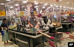 Sejumlah kasir di sebuah supermarket di mal AEON, Tangerang, melayani pembeli dibalik pembatas lapisan plastik untuk mencegah penularan virus corona, 22 Mei 2020. (Foto: AP)