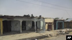 Bloodstains seen on the street and damage buildings following a suicide bomb explosion at a World cup viewing centre in Damaturu, Nigeria, Wednesday, June 18, 2014. Police say 14 people were known to have died in the bombing of an outdoor World Cup viewin