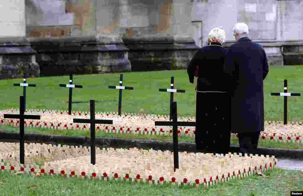 People pause among the crosses and poppies in the Field of Remembrance at Westminster Abbey in London, dedicated to those killed in the current conflict.