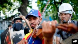 En esta foto de archivo, del 26 de julio, de 2017, Wuilly Arteaga toca el violín durante enfrentamientos con la Guardia Nacional Bolivariana en Caracas durante protestas por la Asamblea Constityente propuesta por el gobierno del presidente Nicolás Maduro.