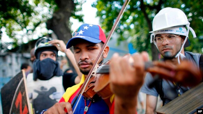 En esta foto de archivo, del 26 de julio, de 2017, Wuilly Arteaga toca el violín durante enfrentamientos con la Guardia Nacional Bolivariana en Caracas durante protestas por la Asamblea Constityente propuesta por el gobierno del presidente Nicolás Maduro.