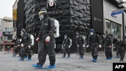 FILE - South Korean health officials from Bupyeong-gu Office wearing protective gear, spray disinfectants at a shopping district in Incheon on Sept. 17, 2020, amid the COVID-19 pandemic.