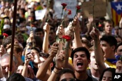 People gesture and wave flowers during a protest in Barcelona, Spain Thursday, Sept. 21, 2017.