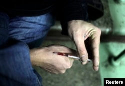 A drug user injects heroin into his hand on a staircase in an apartment block in Moscow, Russia, Nov. 14, 2010.