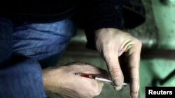 A drug user injects heroin into his hand on a staircase in an apartment block in Moscow, Russia, Nov. 14, 2010. 