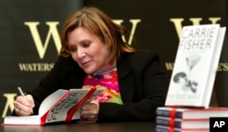 FILE - In this Feb. 20, 2004, photo, "Star Wars" actress, humorist and author Carrie Fisher autographs her book "The Best Awful" at a promotional event in London.