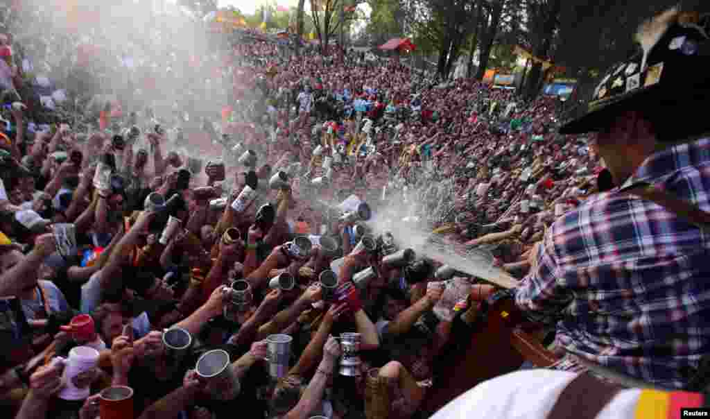 Visitors try to fill their mugs as beer is sprayed on them from a barrel at Argentina&#39;s Oktoberfest, the national beer festival, in Villa General Belgrano, Argentina, Oct. 9, 2016.