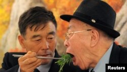 Con trai Ryu Young-il (trái) ở Bắc Triều Tiên gắp đồ ăn cho người cha Ryu Hae-chan ở miền Nam trong một cuộc sum họp gia đình. Hai cha con đã bị ly tán kể từ cuộc Chiến tranh Triều Tiên.