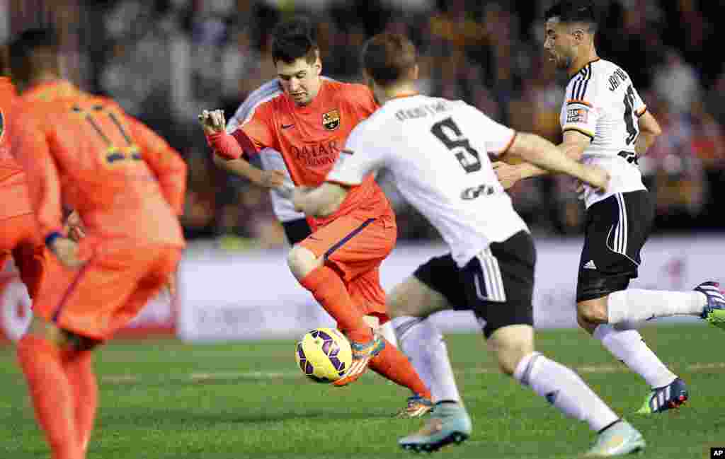 L&#39;Argentin Lionel Messi de Barcelone fait une passe à Mustafi de Valence lors d&#39;un match de football de La Liga espagnole au stade Mestalla à Valence, en Espagne, le dimanche 30 novembre 2014.